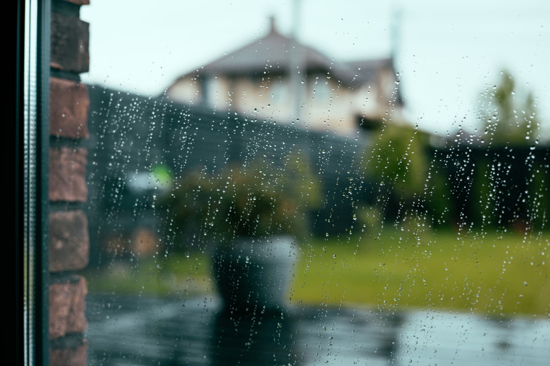 Rain on a window looking out at a house